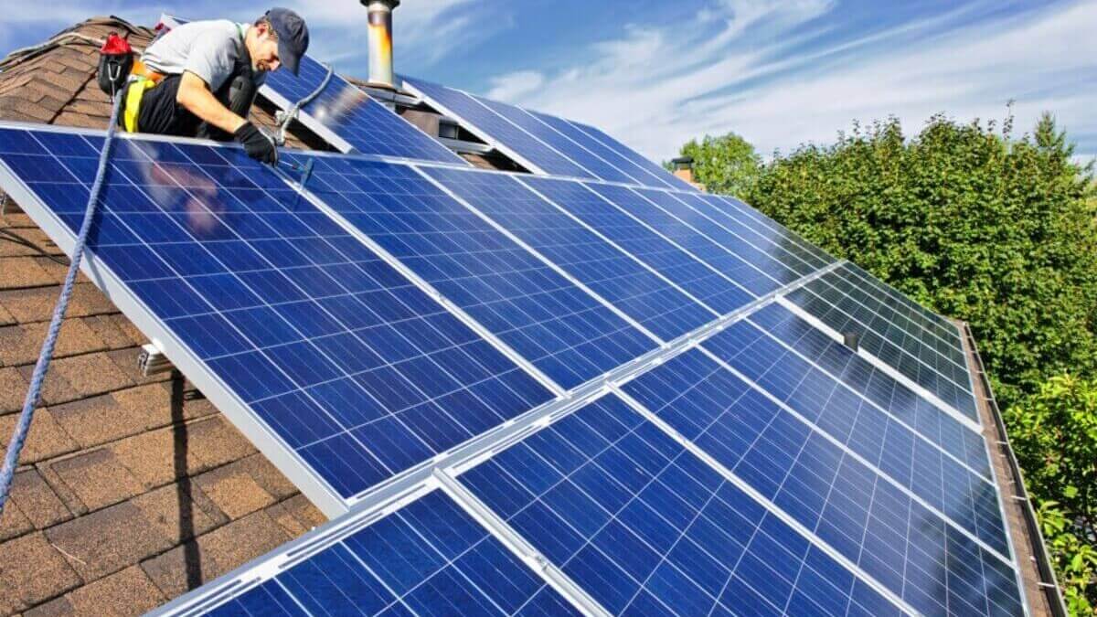 A man working on a solar panel on a roof.