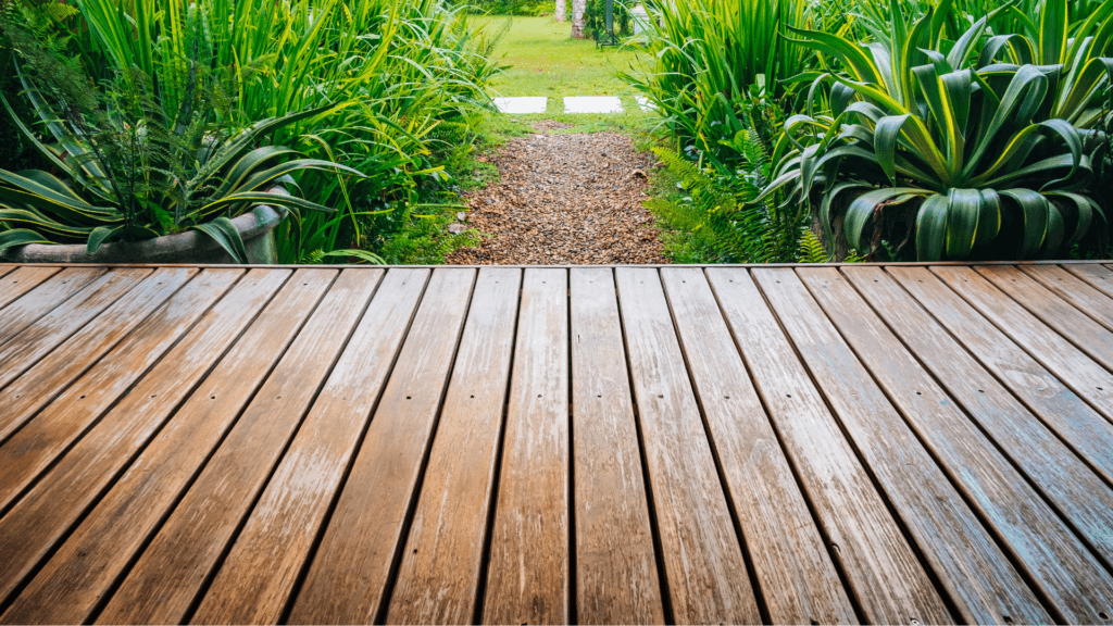 Close-up angle of a wooden deck, with a green garden and lawn in the background.