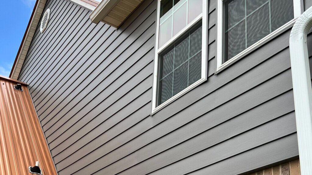 a gray siding of a house with two windons.