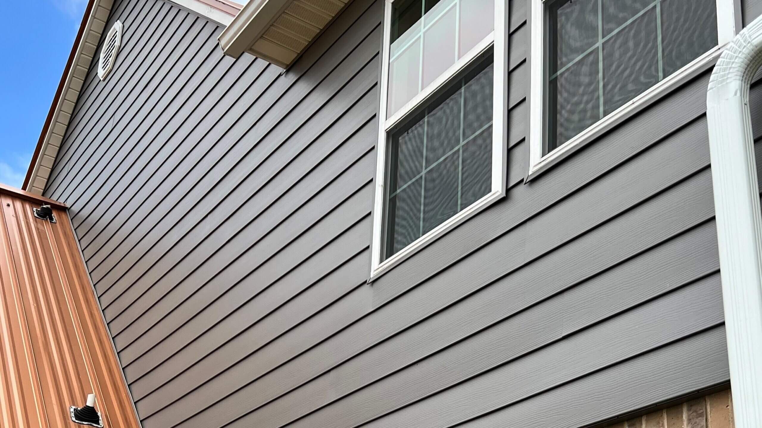 a gray siding of a house with two windons.