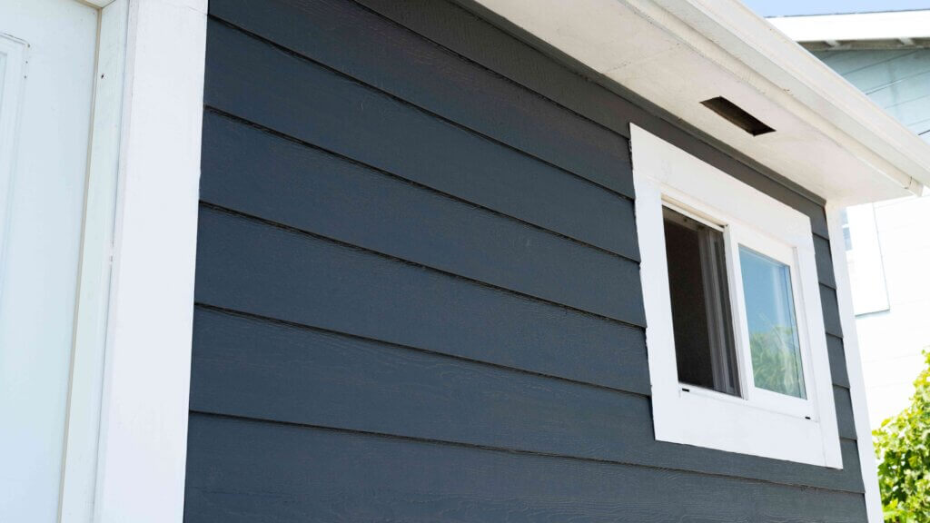 side view of a blue siding with a white window and a white roof.