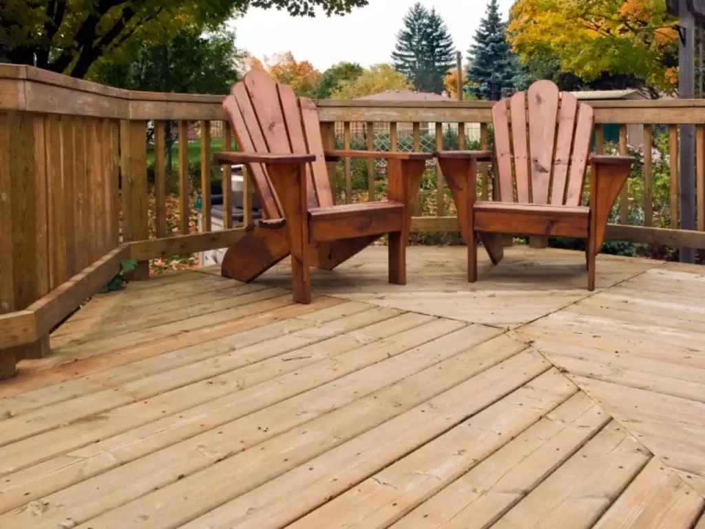 wood deck with two wood chairs and a wood fence in the background.