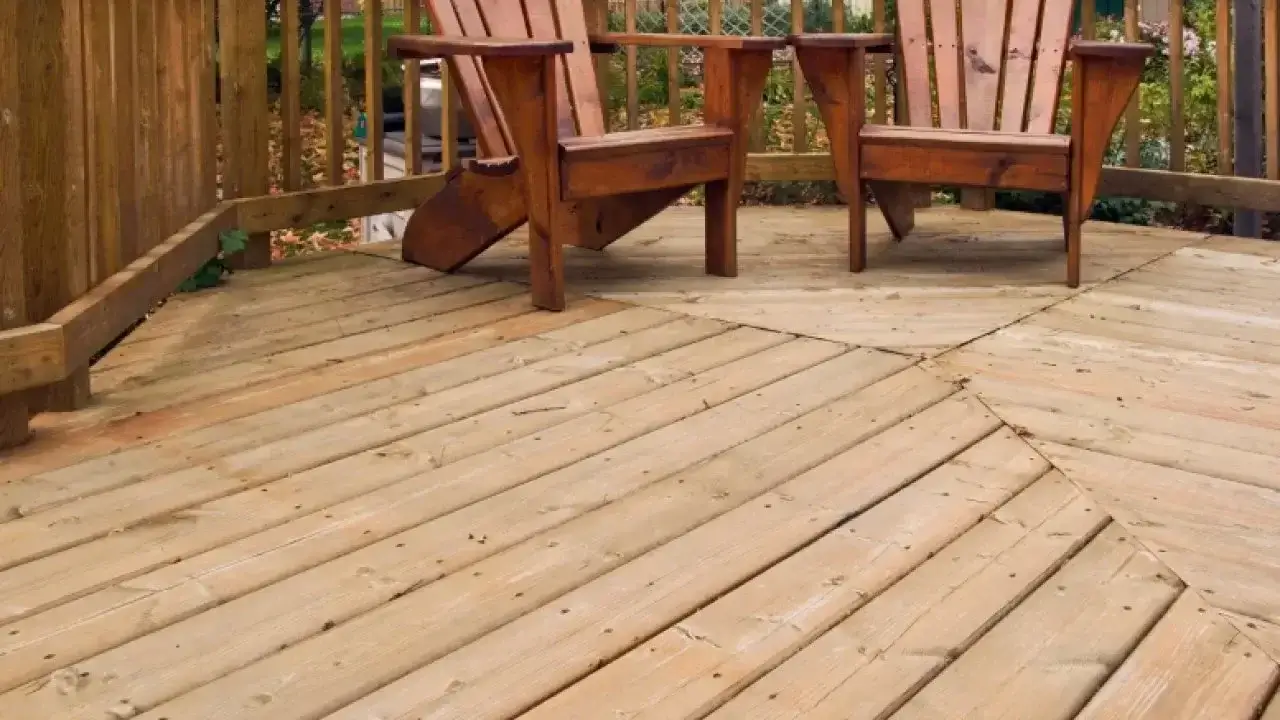 wood deck with two wood chairs and a wood fence in the background.