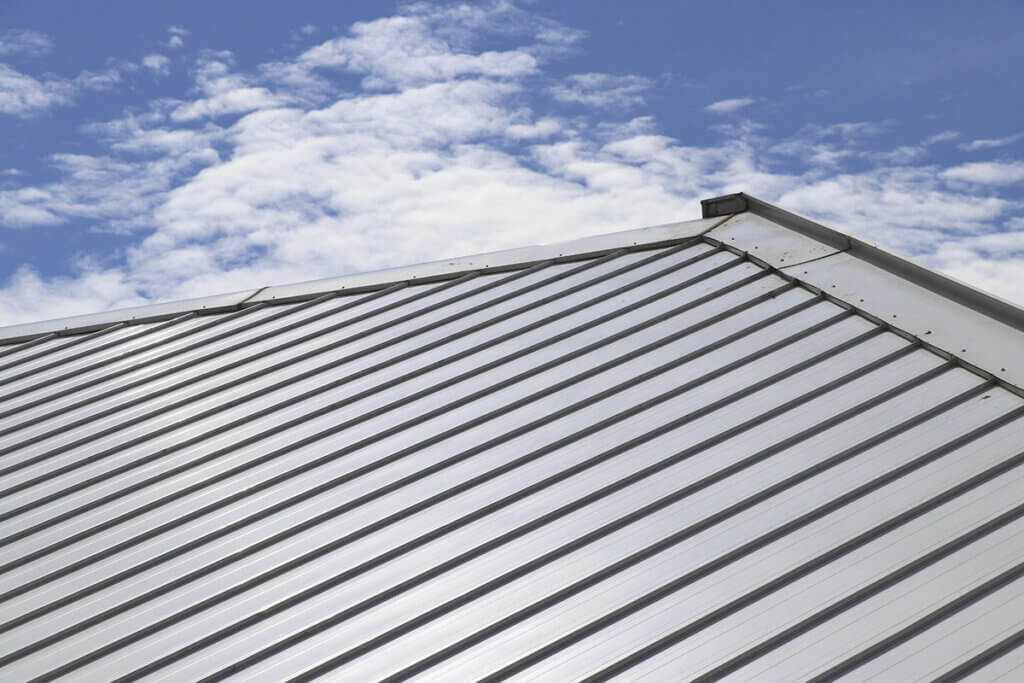 metal grey cool roof with a blue sky with some clouds in the background.