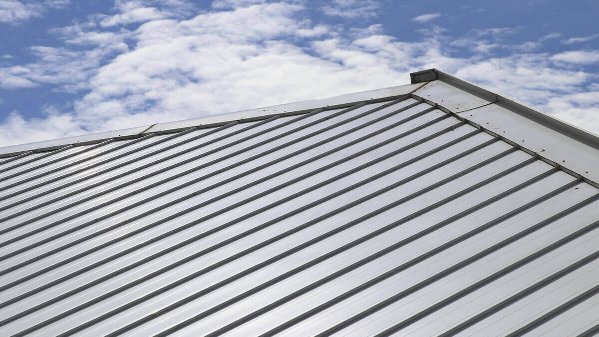 metal grey cool roof with a blue sky with some clouds in the background.