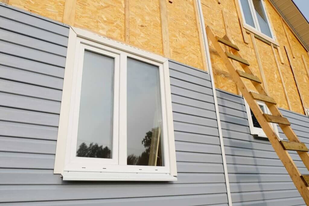 the front of a house with a blue siding being installed.