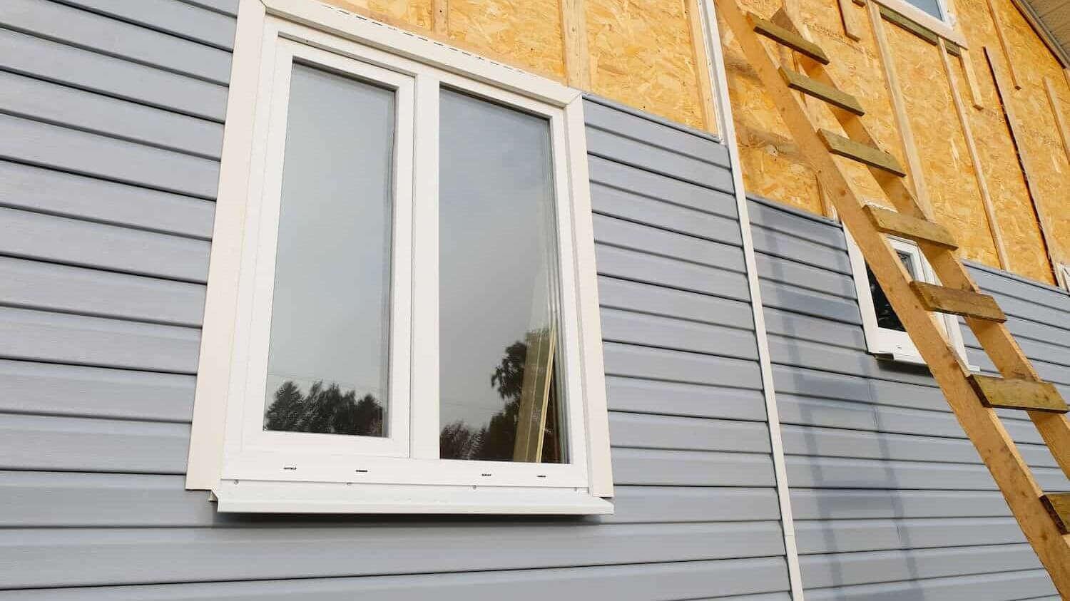 the front of a house with a blue siding being installed.